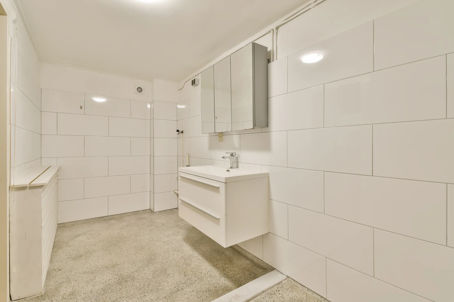 A-BATHROOM-WITH-WHITE-TILES-AND-A-SINK-AND-MIRROR-2023-11-27-04-52-20-UTC