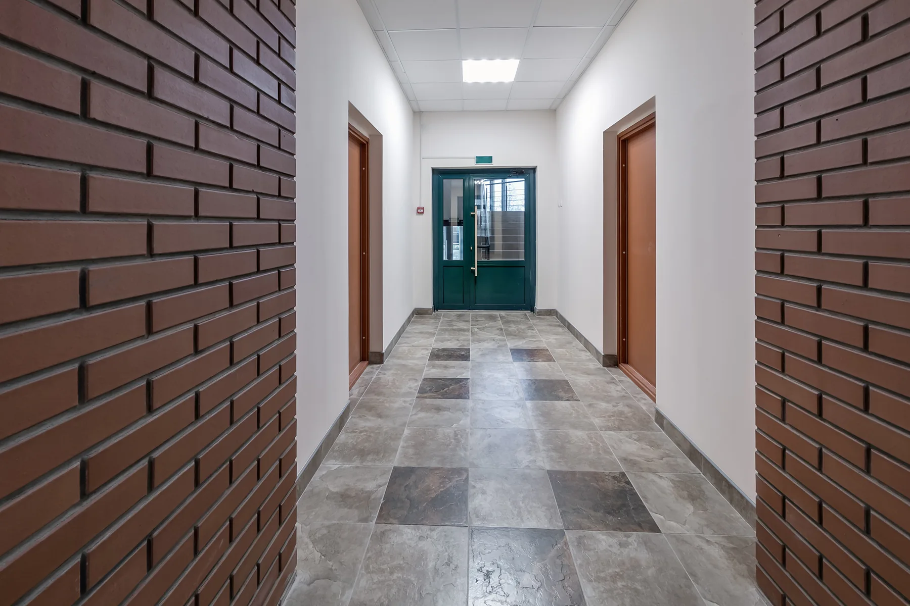 WHITE-EMPTY-LONG-CORRIDOR-WITH-RED-BRICK-WALLS-FOR-2023-11-27-05-14-06-UTC